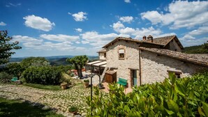 A stone building with a tiled roof, a small porch, and a view of the surrounding landscape. - RIPOSTENA COUNTRY HOUSE The Shed (Casole)