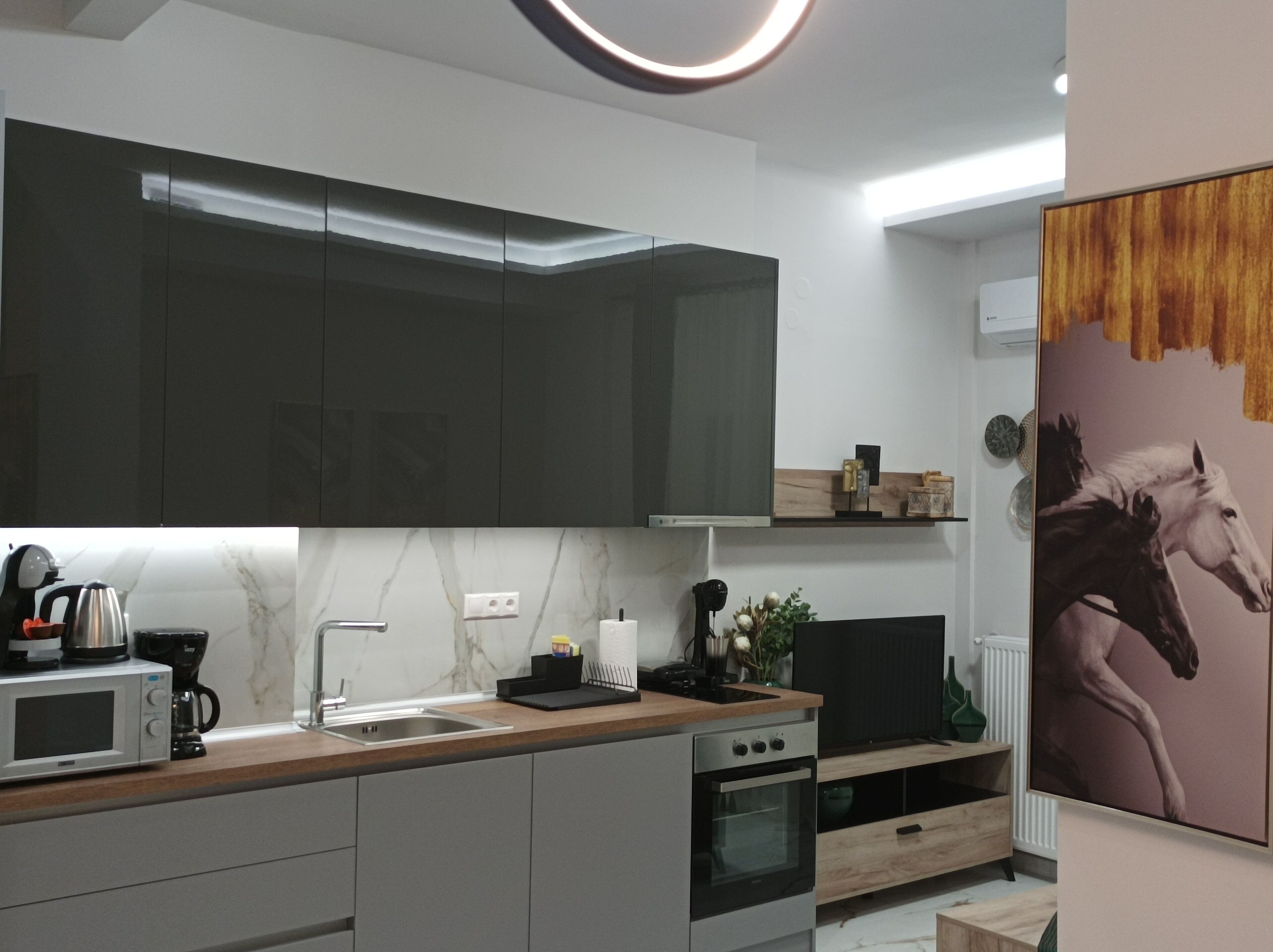 A modern kitchen with dark cabinets, a marble backsplash, and a wooden countertop.