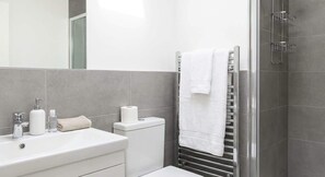 A modern bathroom with a white sink, toilet, and towel rack. - Comfortable 1BR Apartment in Manchester (Manchester)