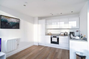 A modern kitchen with white cabinetry, a built-in oven, a microwave, and a sink. - Comfortable 1BR Apartment in Manchester (Manchester)