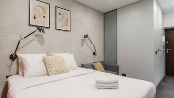 A modern hotel room with a large bed, two wall-mounted lamps, and two framed abstract artworks.
