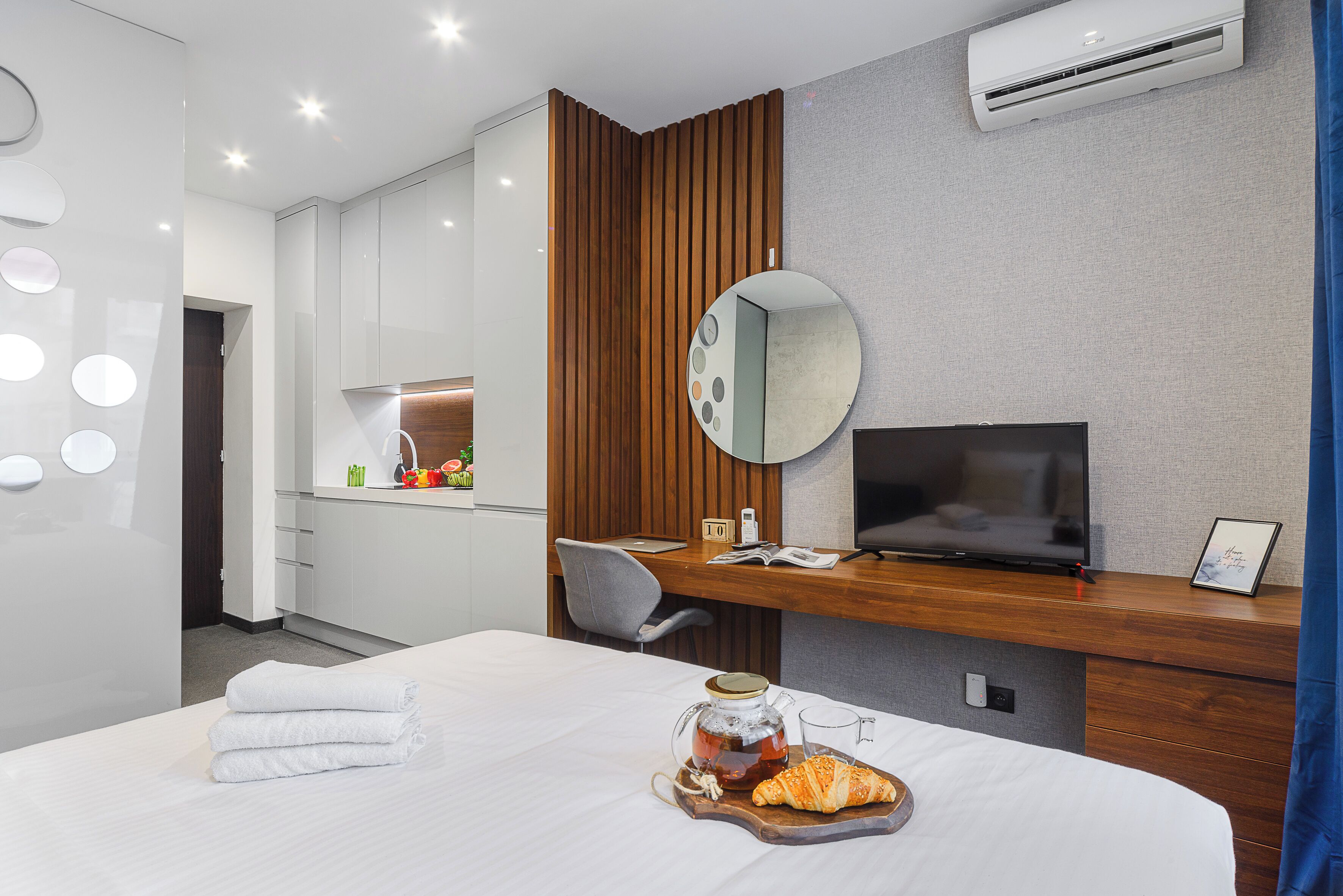 Moderni hotellihuone, jossa on sänky, televisio, työpöytä ja taustalla näkyvä kylpyhuone.