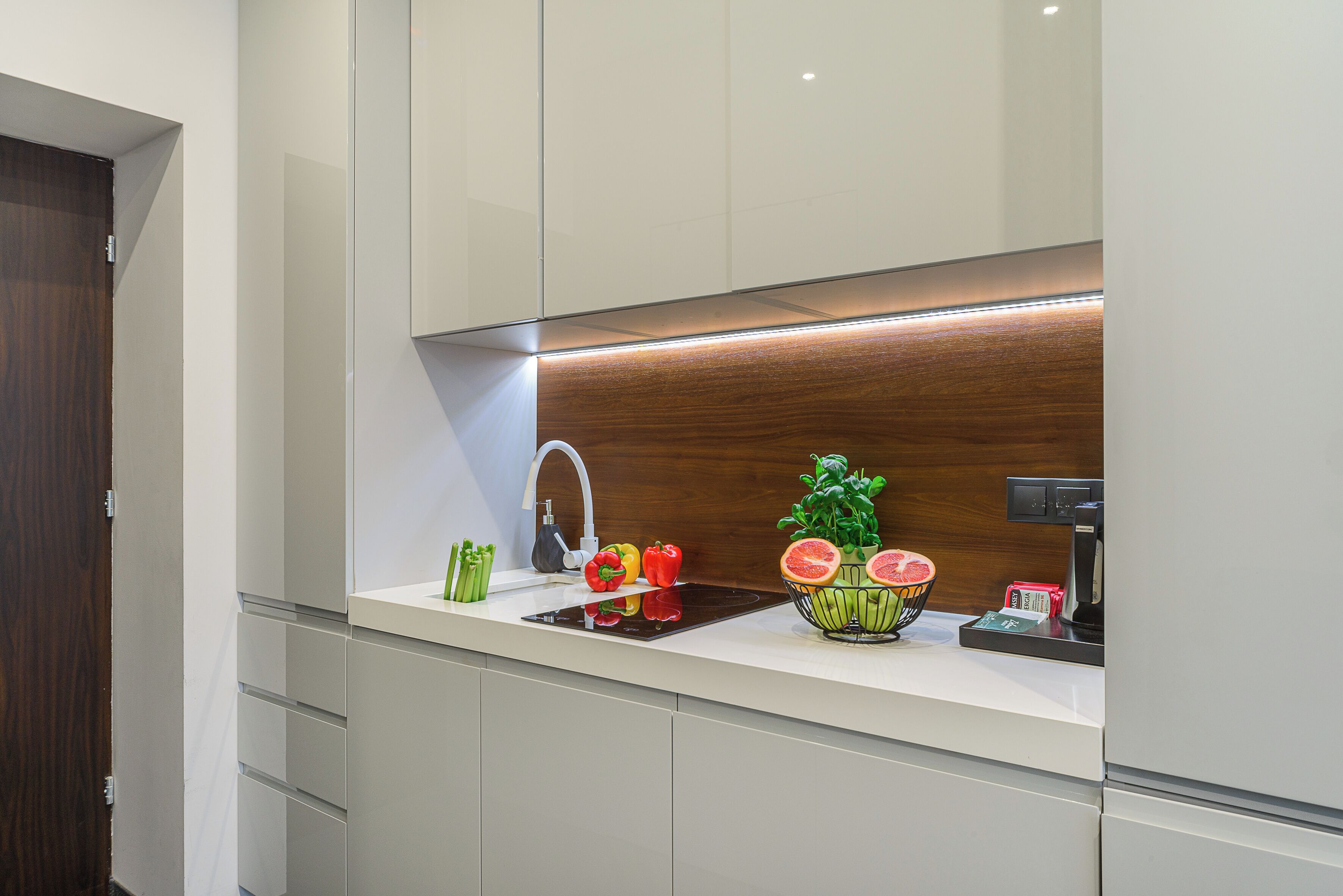 Una cocina moderna con un lavamanos integrado, un protector contra salpicaduras de madera y una encimera con verduras frescas y una máquina de café.