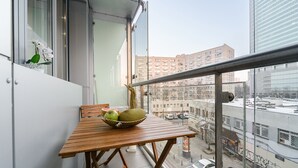 Un balcón con una mesa de madera, un cuenco de fruta y una planta en maceta.