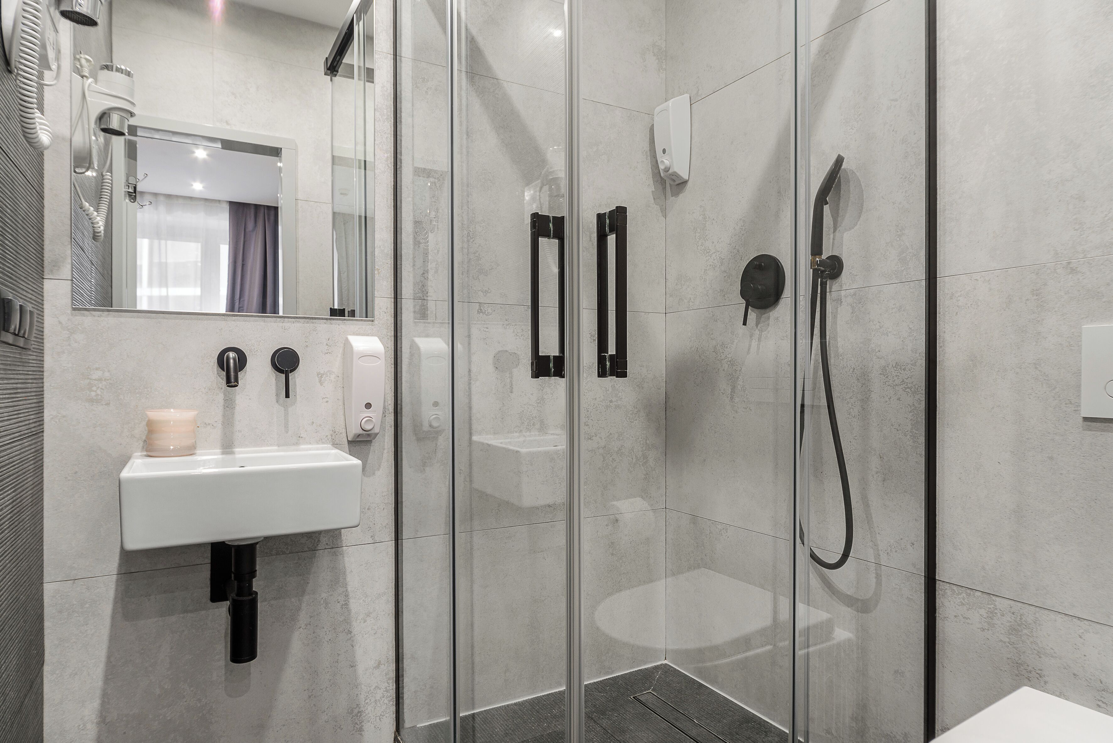 A modern bathroom with a glass-enclosed shower, a white sink, and a mirror above the sink.