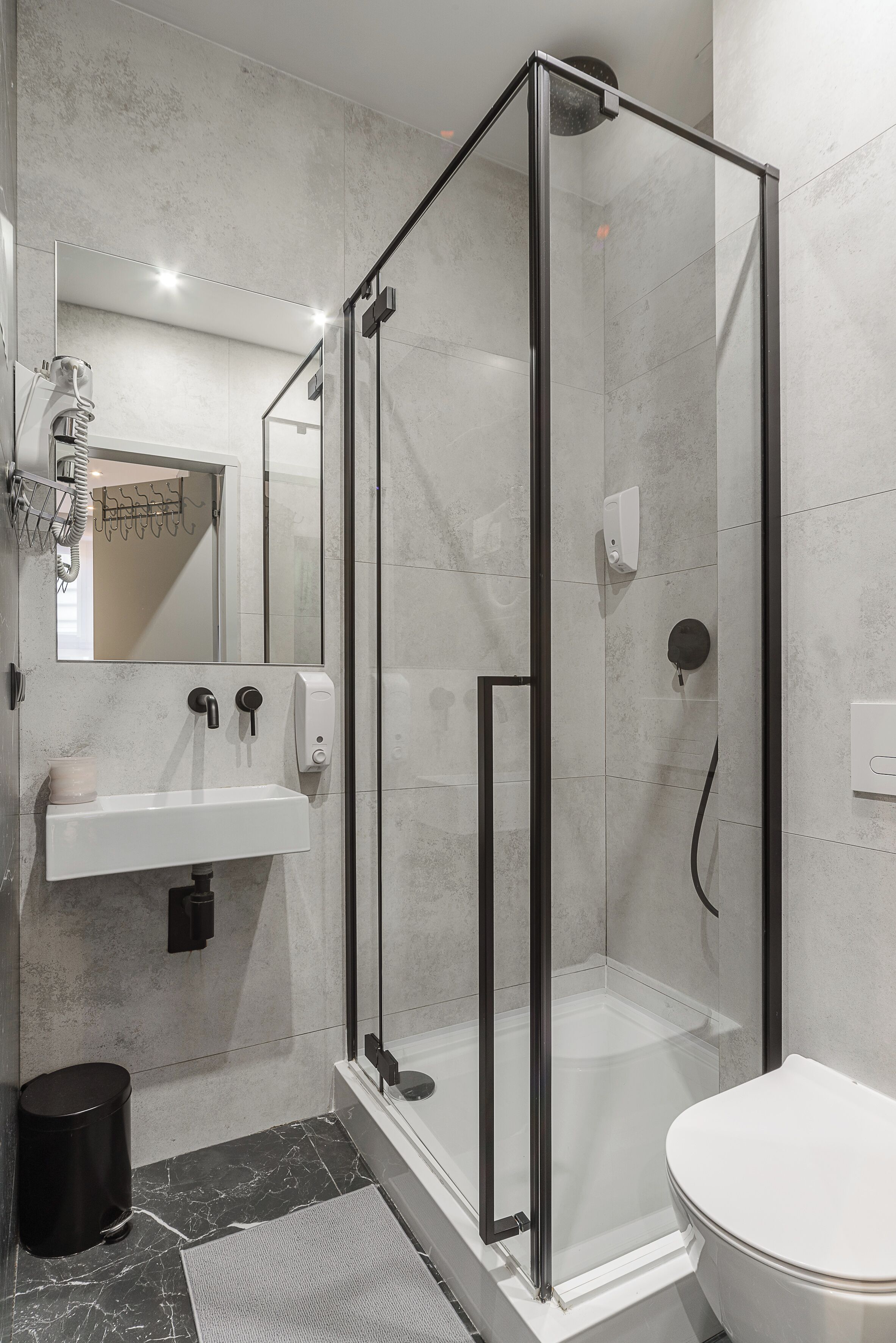 Een moderne badkamer met een douchecabine van glas, een wastafel met spiegel, en een toilet.