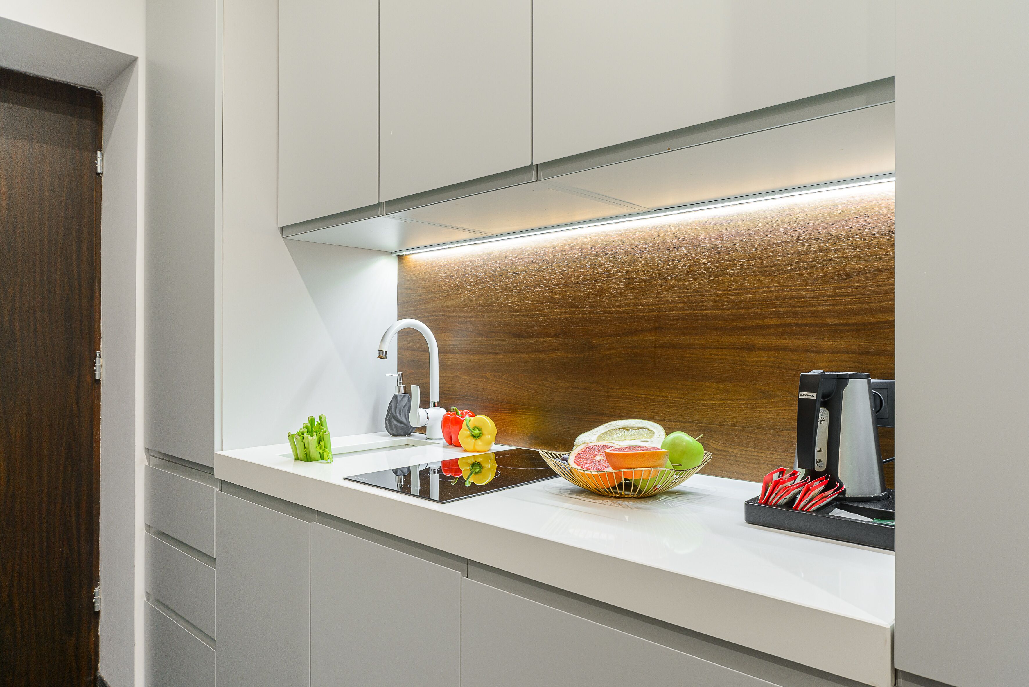 A modern kitchen with a built-in sink, a coffee machine, and a fruit bowl on the counter.