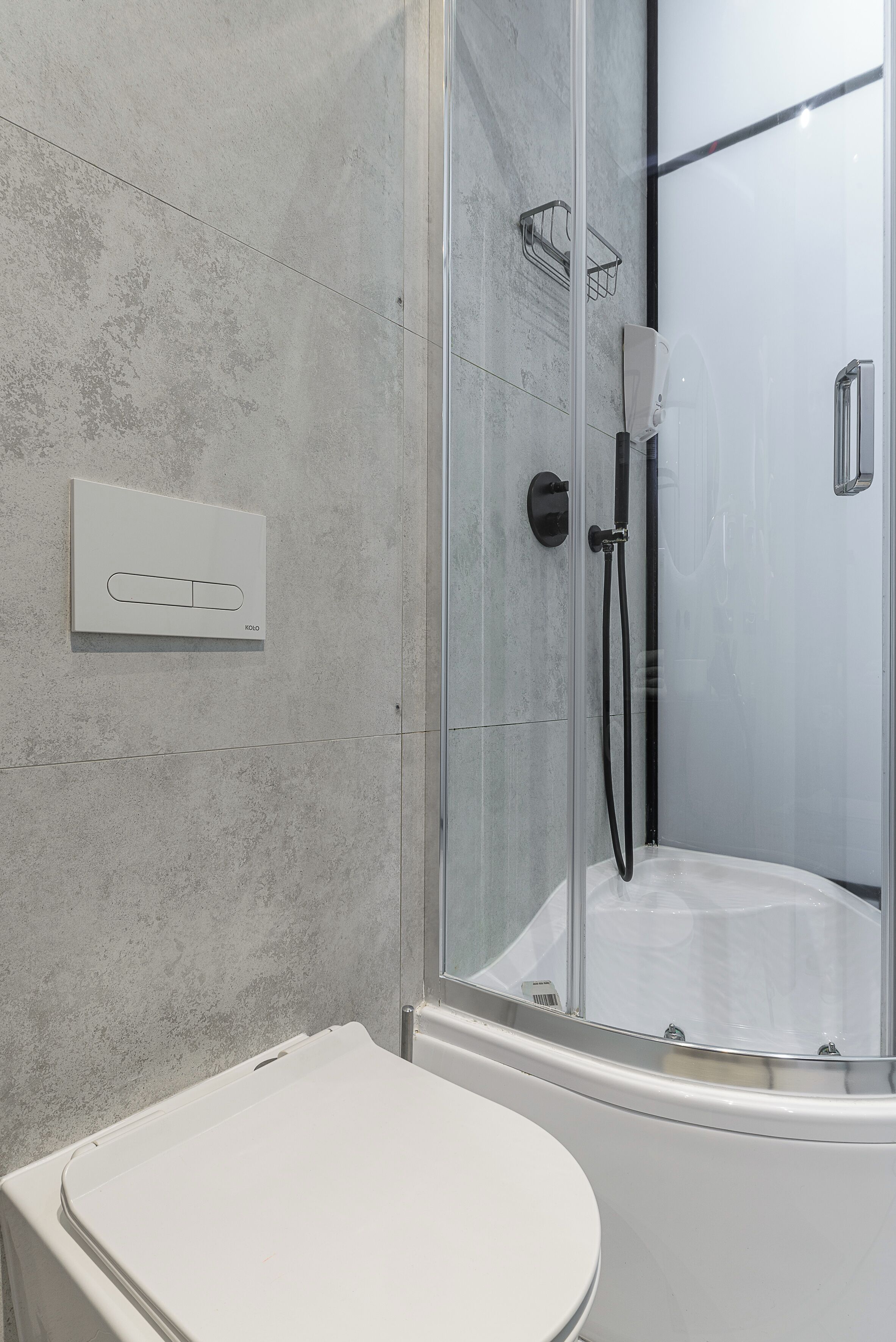 Un baño moderno con ducha de vidrio, un inodoro blanco y un perchero en la pared.