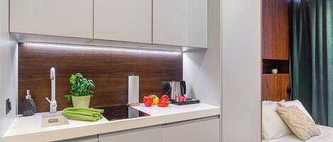 A modern kitchen with a built-in stove, a sink, and a countertop with a plant and vegetables.
