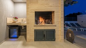 Una cocina moderna con chimenea empotrada, un refrigerador pequeño y una encimera con un florero.