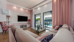 Una sala de estar moderna con un sofá, una mesa de centro de vidrio, un televisor de pantalla plana y una chimenea.