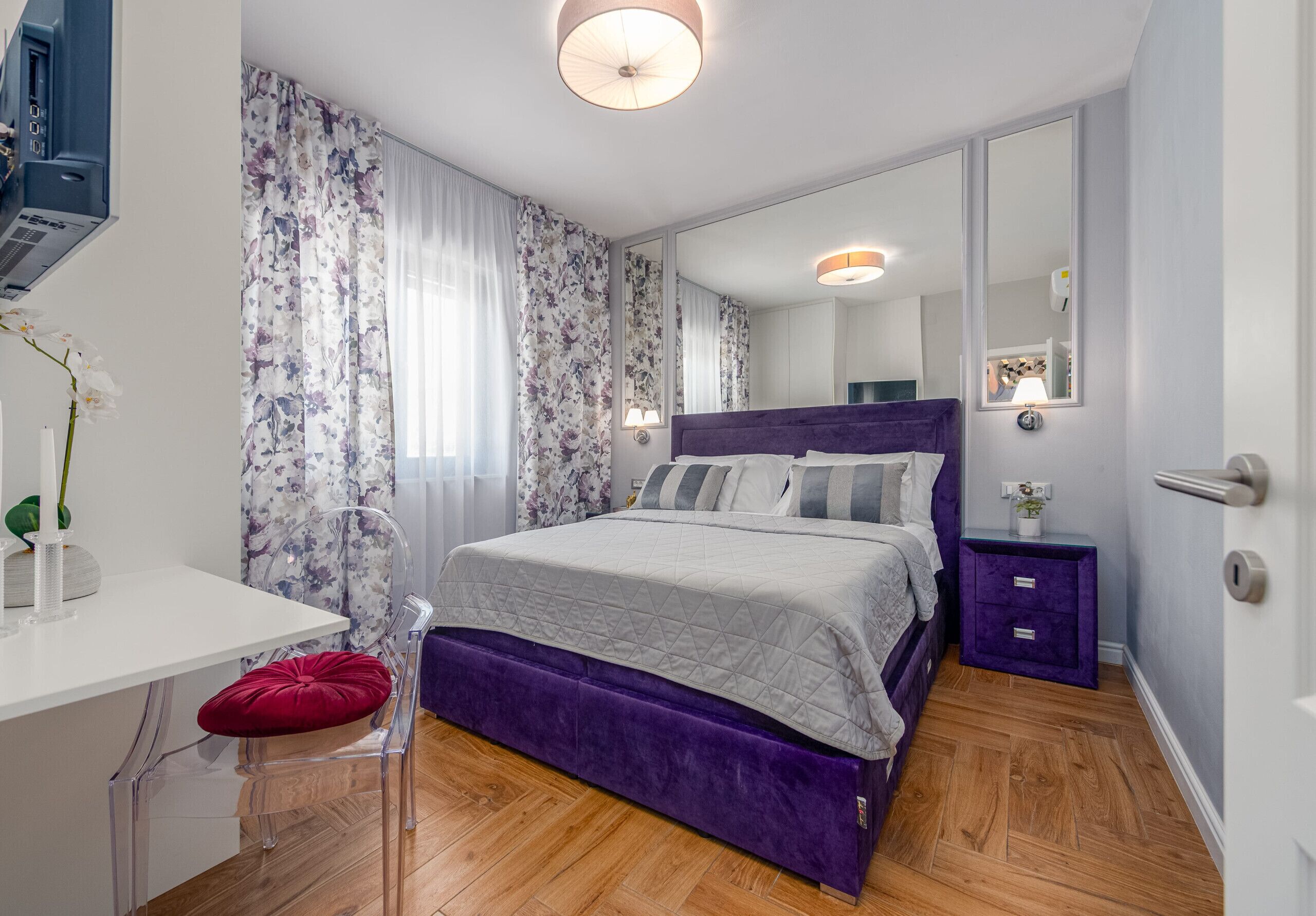 A modern bedroom with a bed, a desk, a chair, and a mirror.