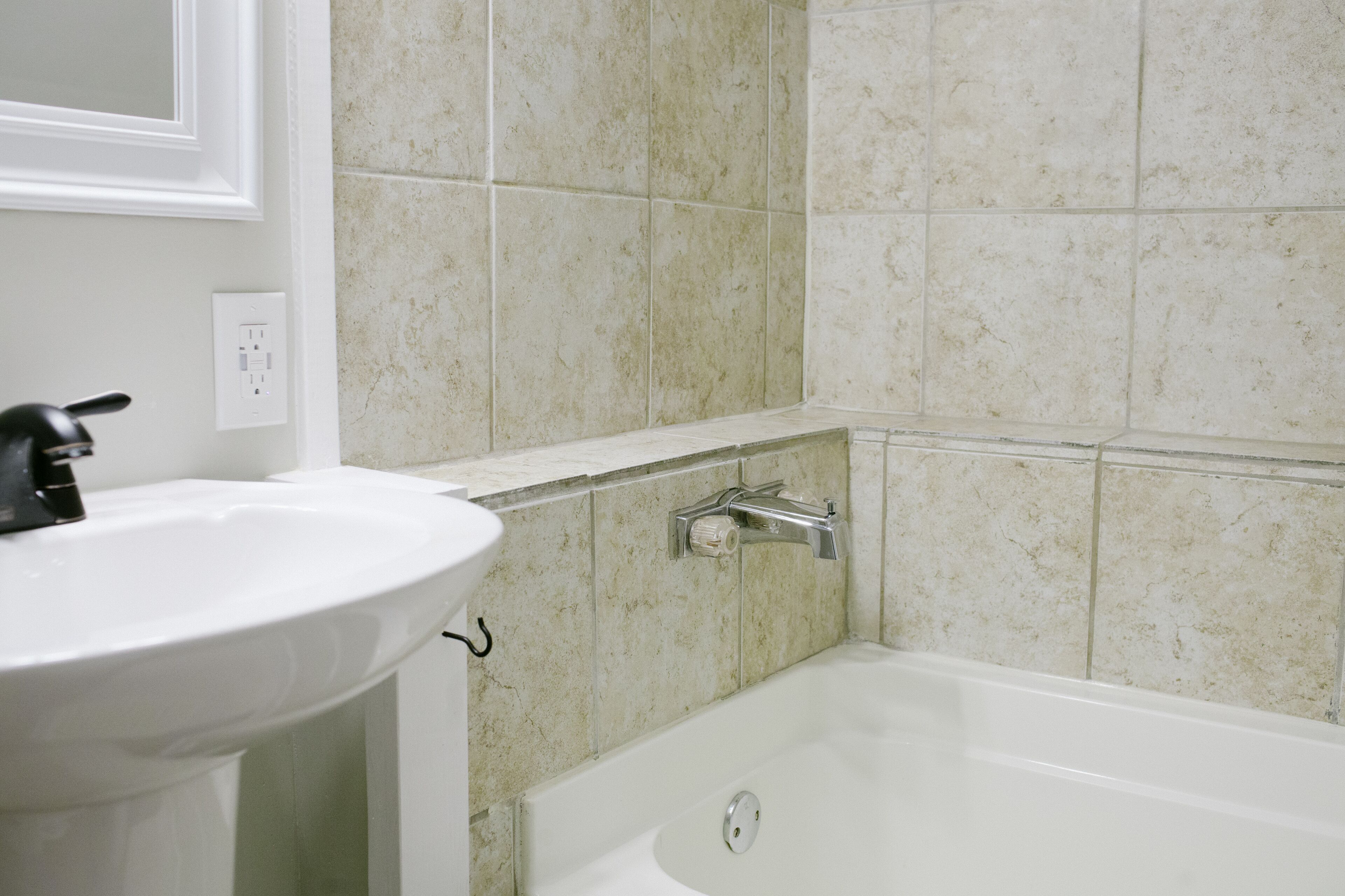 A bathroom with a white sink, a bathtub, and a toilet.