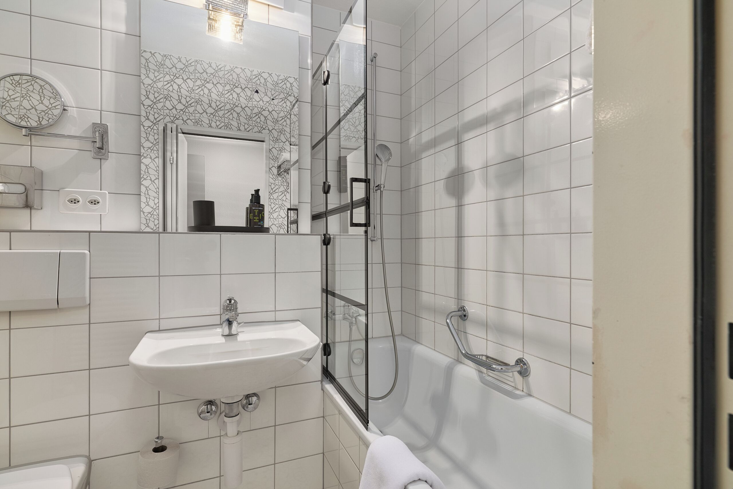 Un baño moderno con lavamanos, espejo y ducha.