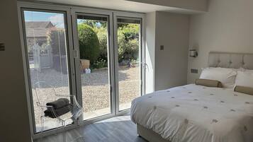A bedroom with a large bed, a sliding glass door leading to a garden, and a modern design.