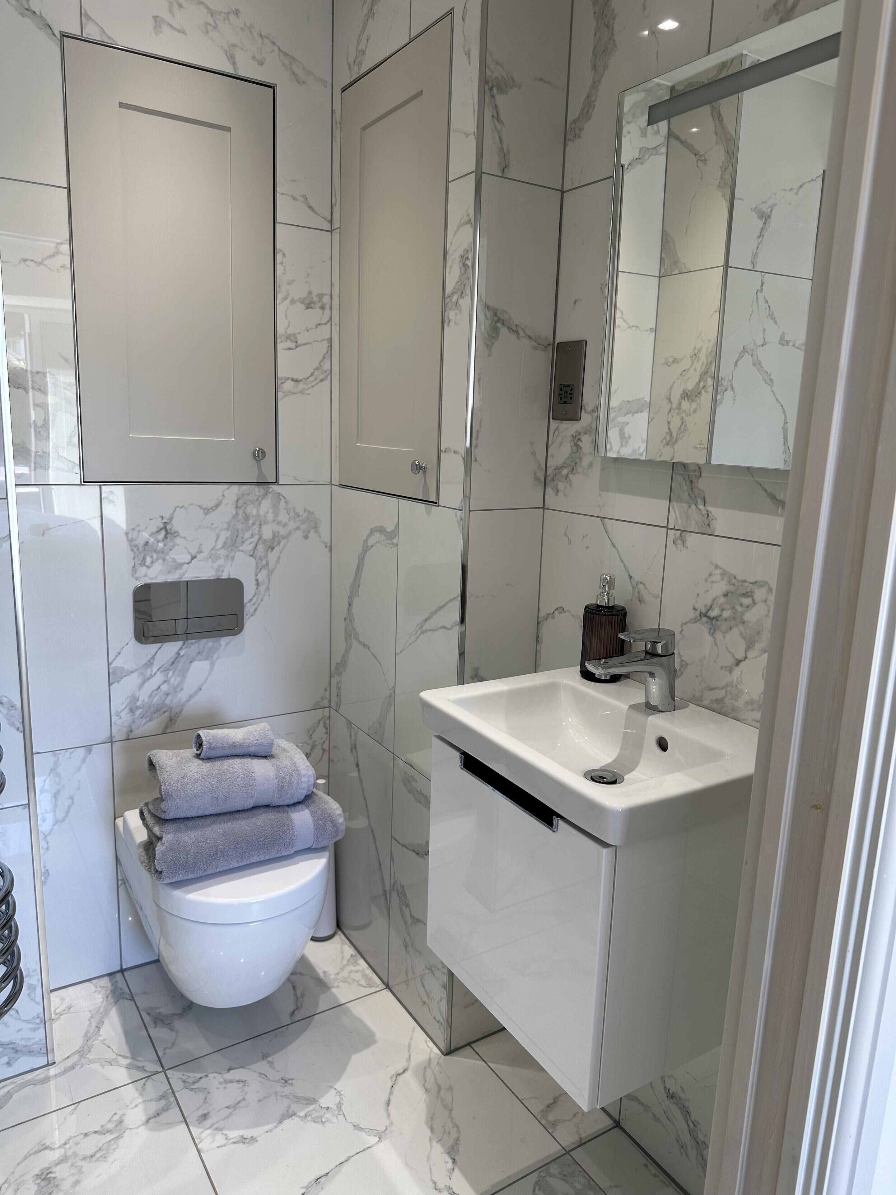A modern bathroom with a toilet, sink, and mirror.