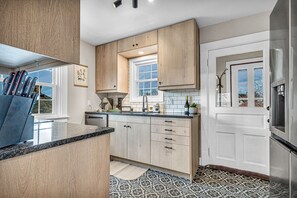 A kitchen with wooden cabinets, a black countertop, and a tiled backsplash.