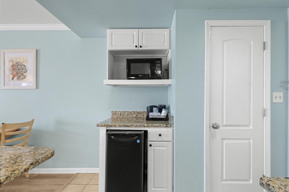 A compact kitchen with a microwave, dishwasher, and a countertop with a coffee maker.