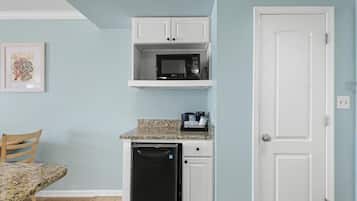 A compact kitchen with a microwave, dishwasher, and a countertop with a coffee maker.