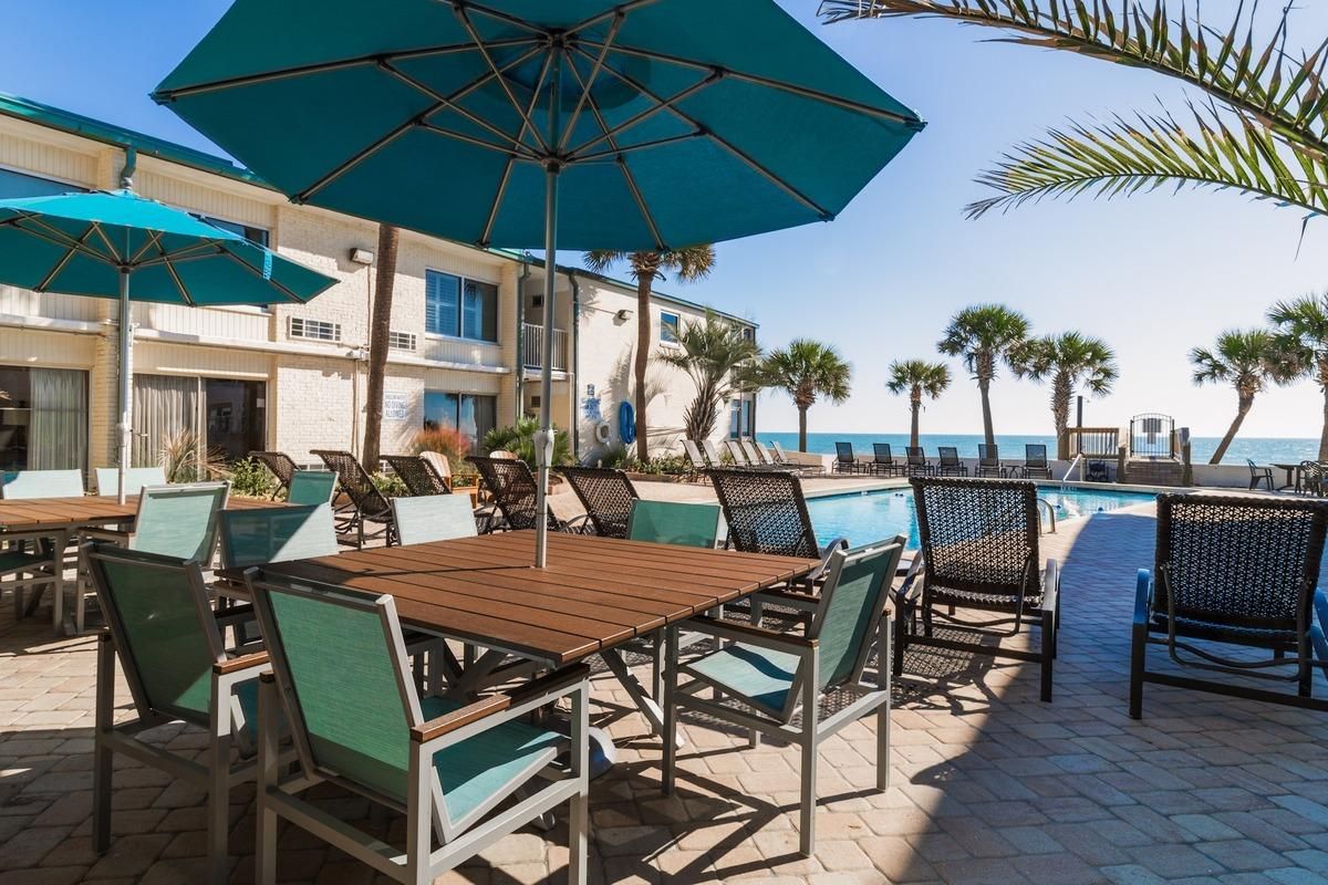 A poolside area with lounge chairs, umbrellas, and a view of the ocean.