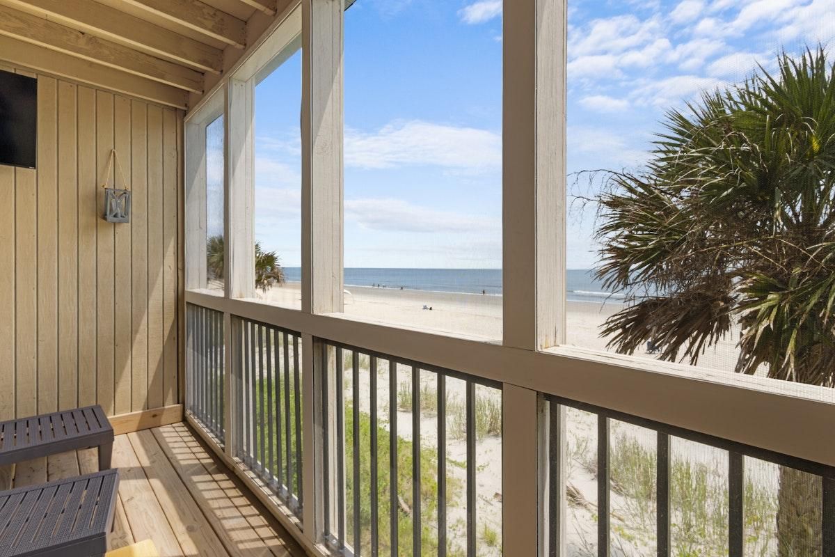 A wooden deck with a view of the beach and palm trees.