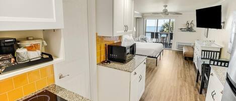 A compact kitchen with white cabinets, a microwave, and a built-in stove.