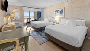 A hotel room with two beds, a dining table, a TV, and a view of the ocean. - Getaway in our Oceanfront Dune Rooms 2nd Floor (Pawleys Island)