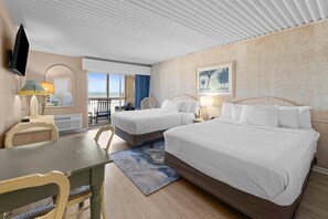 Ein Hotelzimmer mit zwei Betten, einem Esstisch, einem Fernseher und Blick auf das Meer.