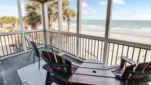 Un espacio de estar al aire libre cubierto con vista a la playa y al océano.