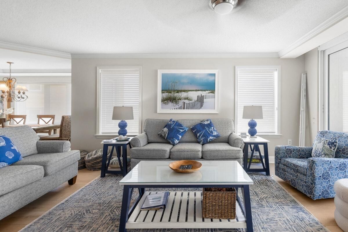A living room with a grey sofa, a patterned armchair, a coffee table, and a painting on the wall.
