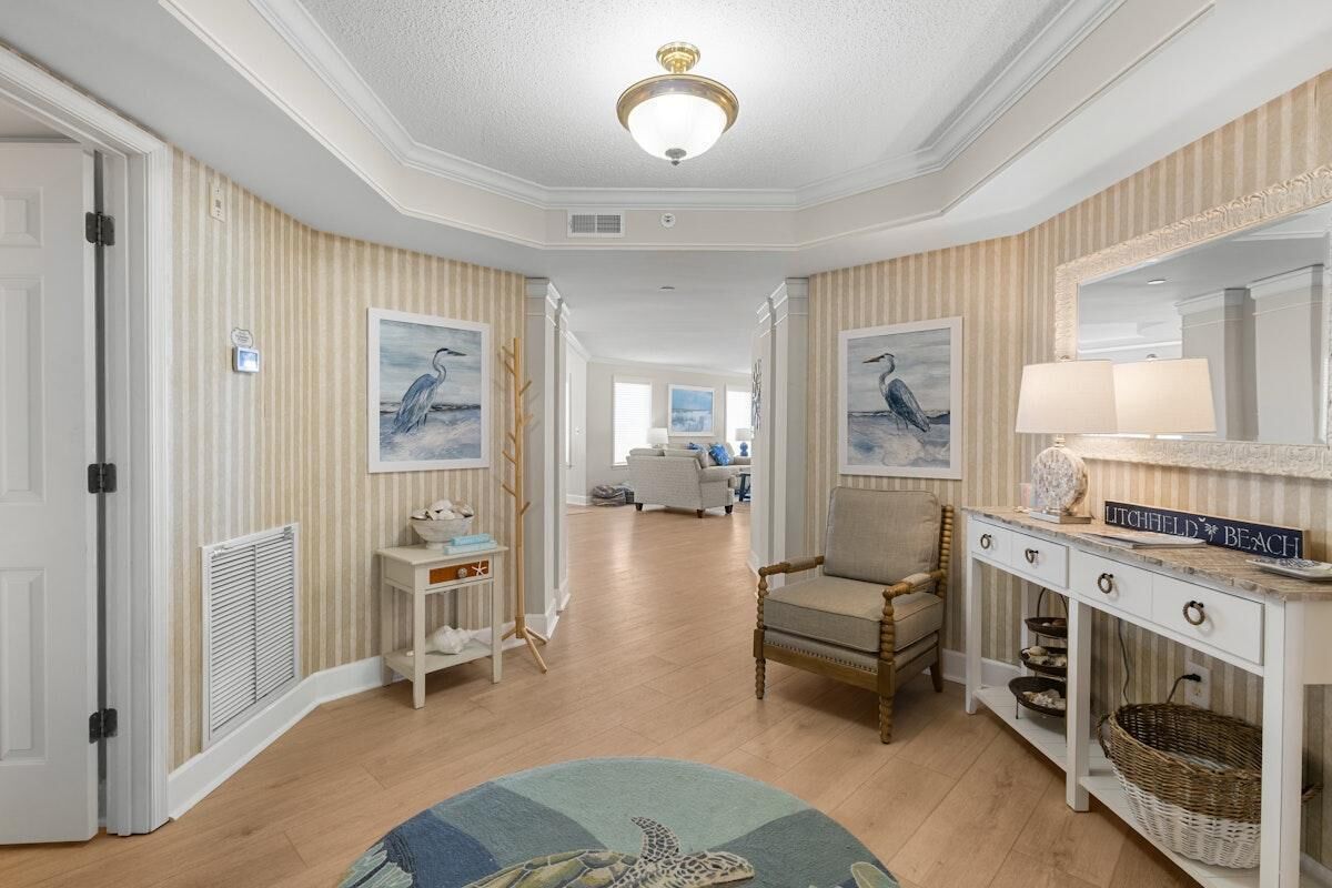 Eine Hotelhalle mit Holzboden, Streifenmuster-Tapete, Deckenventilator, einer Rezeption, einem Stuhl, einer Lampe und einem Schild mit der Aufschrift 'LITCHFIELD BEACH'.