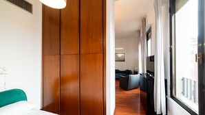 A hotel room with a wooden wardrobe, a bed with white bedding, a desk with a chair, and a view through a window. - Hbhall Brera 59 (Milan)