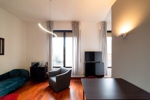 A modern living room with a sofa, a chair, a TV stand, and a table. - Hbhall Brera 59 (Milan)