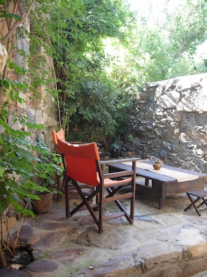 A stone patio with a wooden table and a red chair. - Villa Meli Zachari Fabrica (Perivolia)