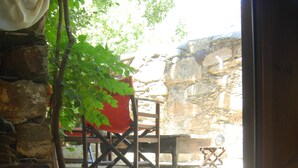 Un muro de piedra rústico, una silla de madera, una mesa y un candelabro con velas.