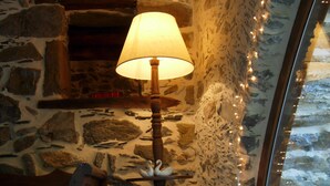Interior de pared de piedra con una lámpara, un cojín y un libro.