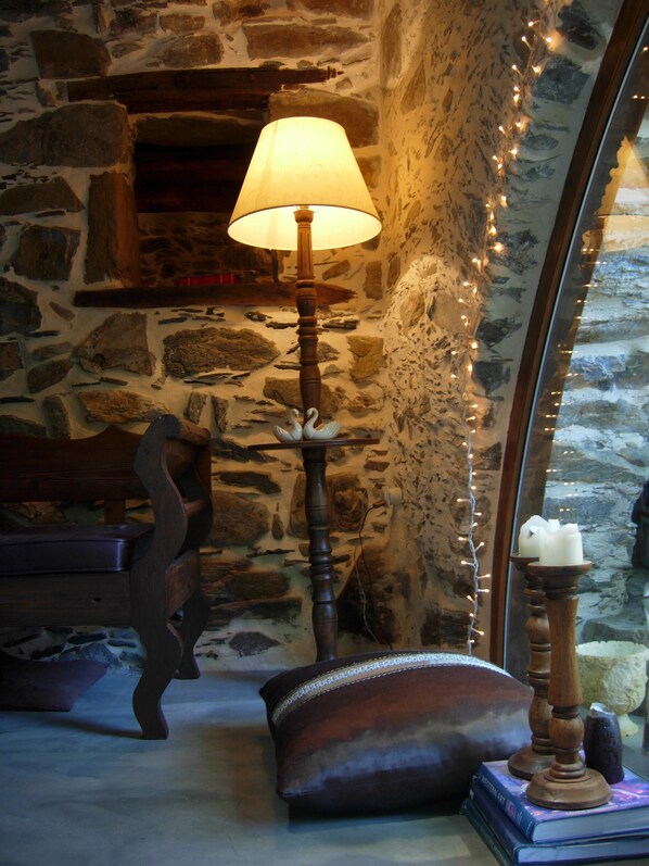 A stone wall interior with a lamp, a cushion, and a book.