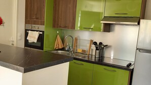 A kitchen with green cabinets, a marble countertop, a stove, a sink, and a paper lantern hanging from the ceiling. - 2 Bedroom Private vacation home in Longeville sur mer (Longeville sur mer)