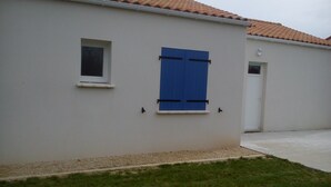 A white building with a tiled roof, a small window, and a door. - 2 Bedroom Private vacation home in Longeville sur mer (Longeville sur mer)
