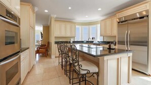 A modern kitchen with a central island, stainless steel appliances, and a dining area with bar stools. - City View Rancho Palos Verdes Home (Rancho Palos Verdes)