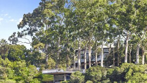 A modern house surrounded by dense trees. - Panoramic Perth Views: 1BR on Mounts Bay Road (Perth)