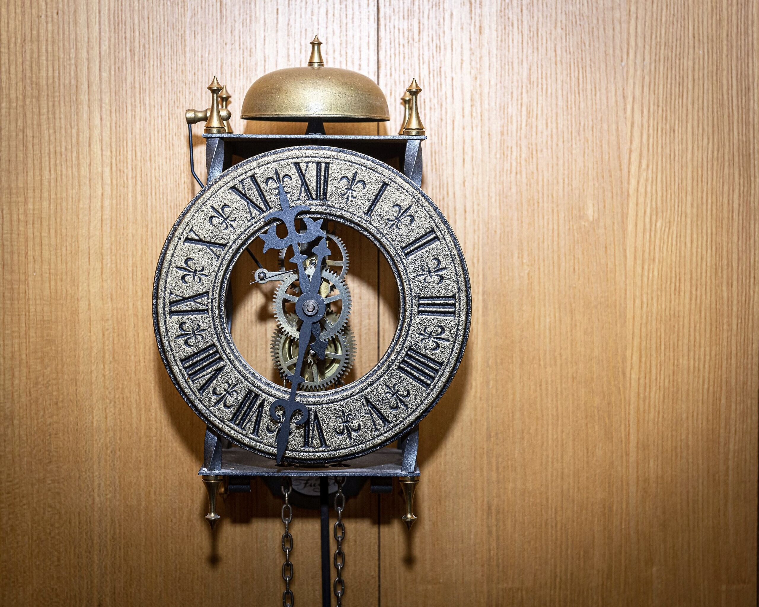 Une horloge murale dotée de chiffres romains et d’un mécanisme à pendule.