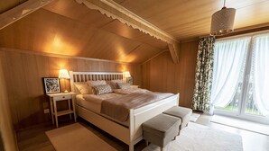 Ein Schlafzimmer mit Holzboden, einem Bett mit Kopfteil, Nachttischen und einem Fenster mit Vorhängen.