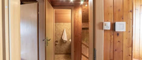 A wooden interior with a shower area, wooden walls, and ceiling lights.