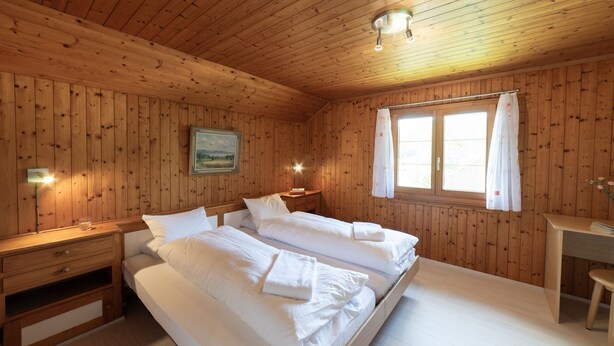 Un dormitorio de cabaña de madera con dos camas, un escritorio y una ventana.