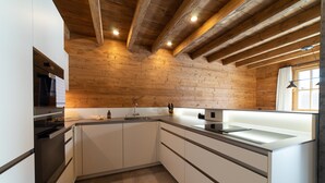 Una cocina moderna con vigas de madera, una isla grande y electrodomésticos integrados.