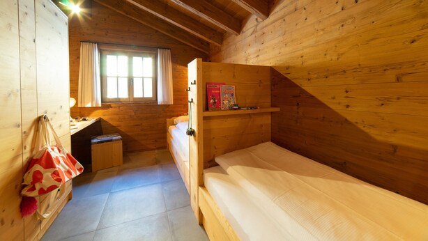 Una habitación de cabaña de madera con una cama, un escritorio y una ventana.