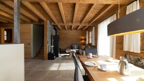 Une cuisine moderne avec un plafond en bois, un coin repas avec une table dressée pour deux personnes, et un escalier menant à un autre niveau.