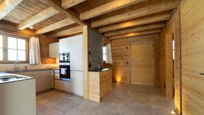 Une cuisine compacte avec des poutres en bois, un four encastré et un mur d’accent en pierre.