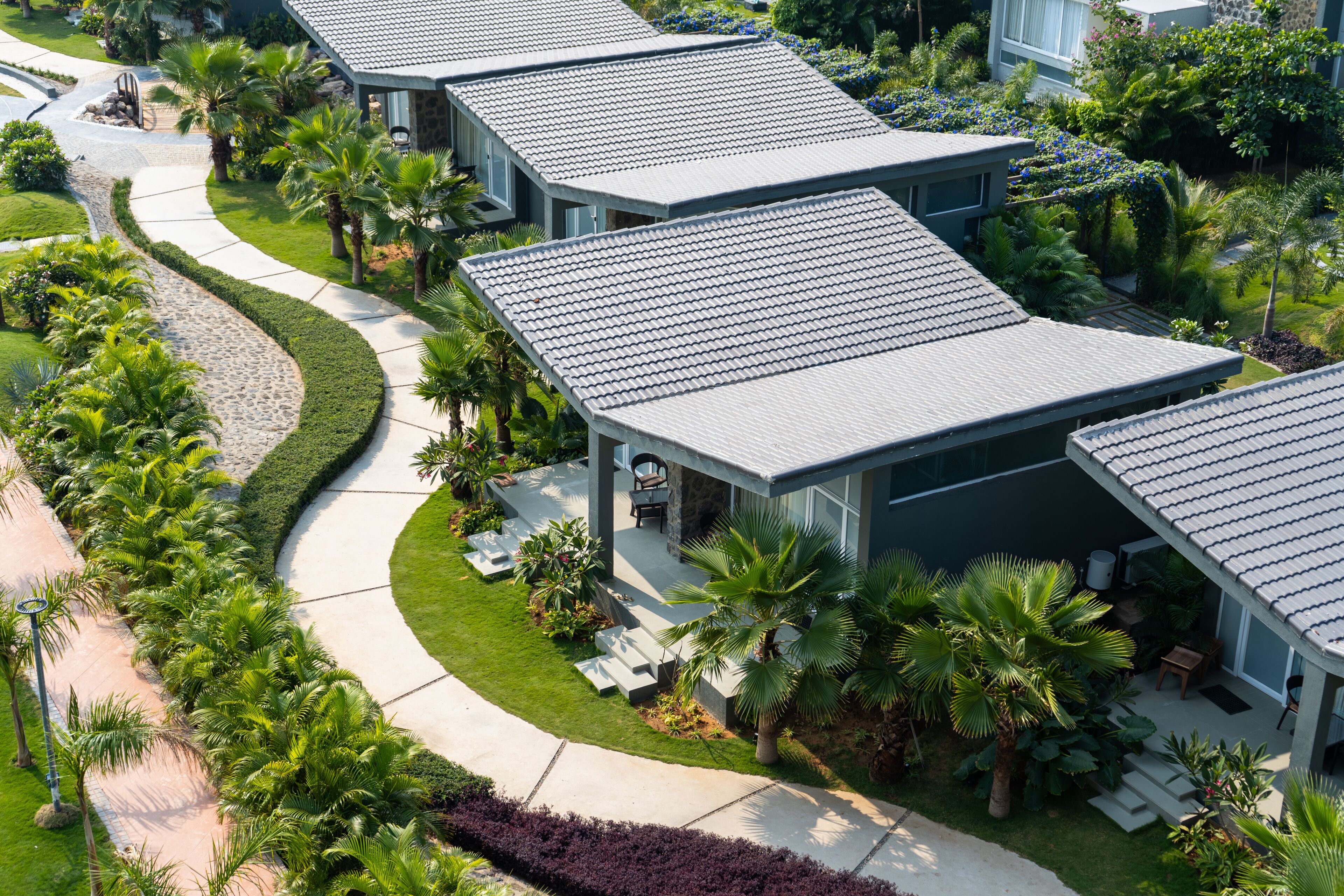 A modern hotel with a curved driveway, outdoor seating, and lush landscaping.